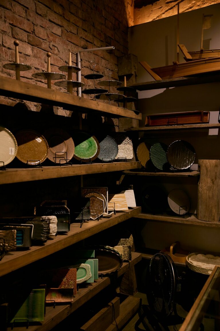 Homeowner compares paint swatches beside a roller, brush, primer, and labeled paint cans.